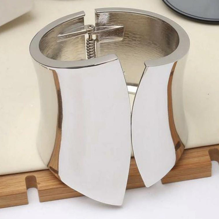 Silver cuff bracelet on a wooden stand with a white background